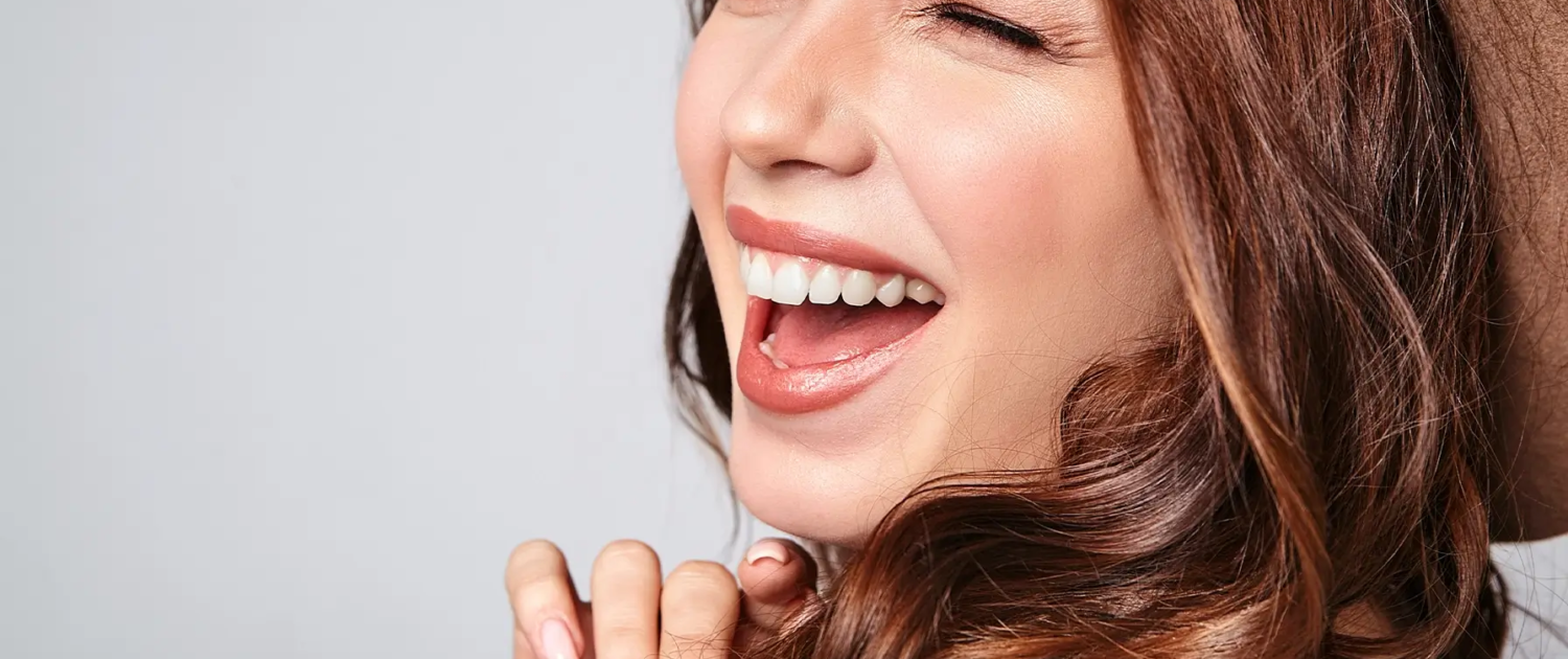 Portrait d'un jeune modèle riant élégant en vêtements d'été décontractés gris dans un chapeau marron avec un maquillage naturel et le résultat de la thérapie Invisalign