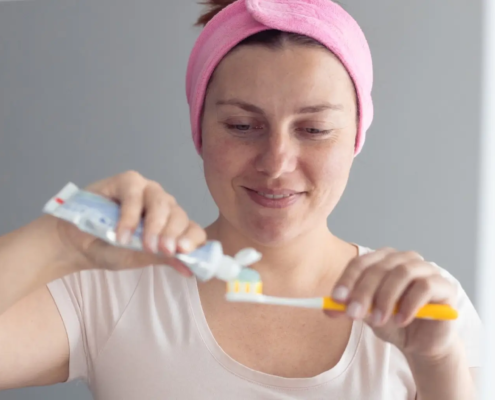 Femme souriante et heureuse se brossant les dents et serrant le dentifrice à la menthe en évitant les restaurations de la carie dentaire