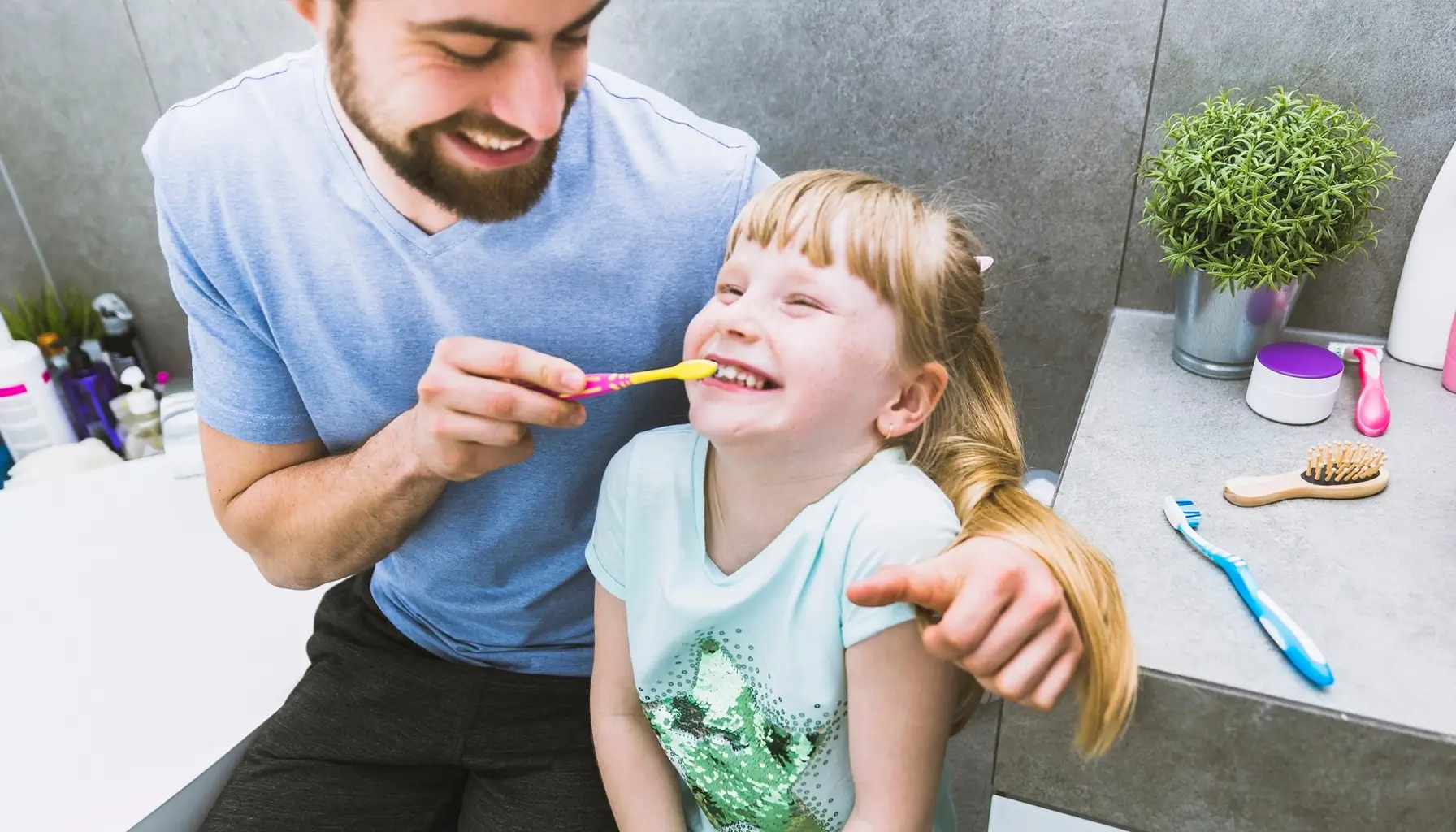 Joyeux père aidant sa fille à se brosser les dents. Il a appris du Dr Parisescu comment utiliser l'Utilisation-du-Fluorure