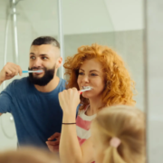 Une joyeuse femme rousse se brossant les dents avec sa famille en évitant une restauration de la carie dentaire