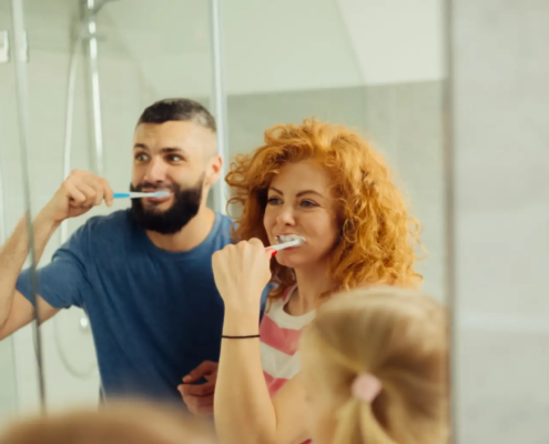 Une joyeuse femme rousse se brossant les dents avec sa famille en évitant une restauration de la carie dentaire