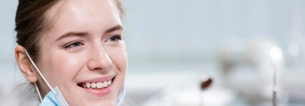 Une belle jeune femme souriante tient des outils dentaires dans ses mains, symbolisant l'importance de l'hygiène buccale.