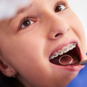 Enfant heureux lors d'une visite chez le dentiste, montrant l'importance du suivi professionnel pour le bien-être bucal et l'hygiène dentaire avec des appareils orthodontiques