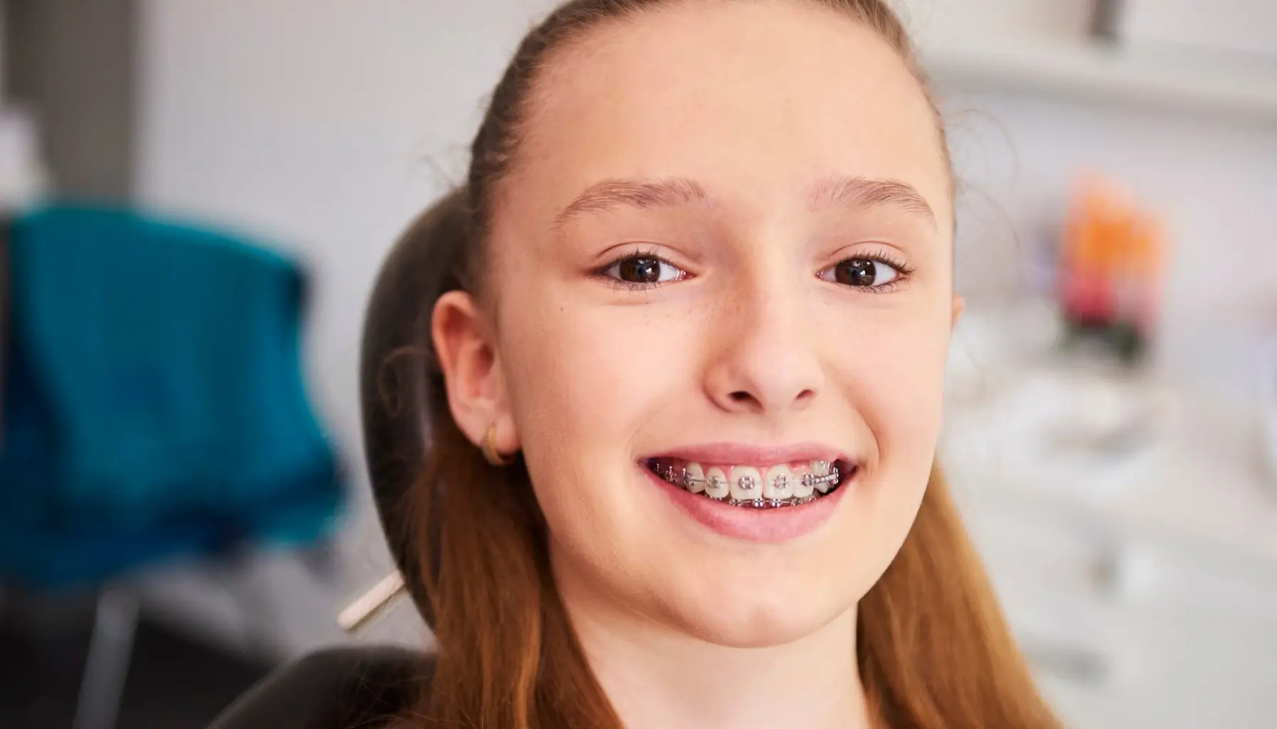 Enfant heureux lors d'une visite chez le dentiste, montrant l'importance du suivi professionnel pour le bien-être bucal et l'hygiène dentaire avec des appareils orthodontiques