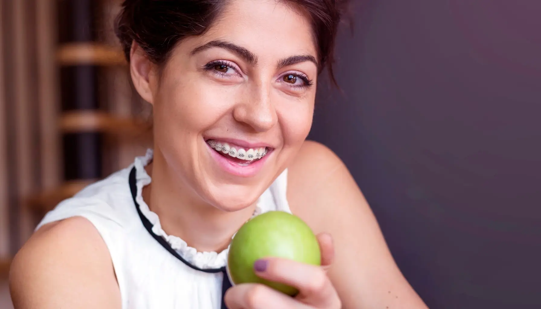 Femme en bonne santé avec une pomme, symbolisant la prévention de l'inflammation par une bonne hygiène buccale