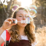 Jeune souriant en plein air, symbolisant une bonne santé dentaire et une alimentation saine, s'amusant avec des bulles rappelant la fraîcheur d'une routine de brossage efficace, en vojage,