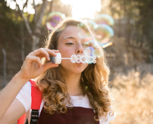 Jeune souriant en plein air, symbolisant une bonne santé dentaire et une alimentation saine, s'amusant avec des bulles rappelant la fraîcheur d'une routine de brossage efficace, en vojage,