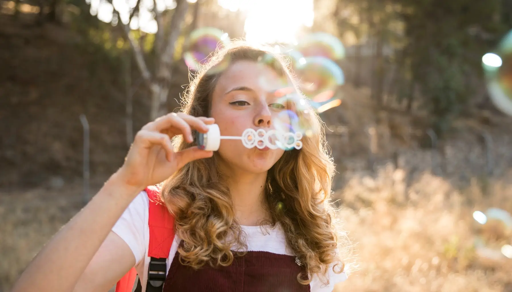 Jeune souriant en plein air, symbolisant une bonne santé dentaire et une alimentation saine, s'amusant avec des bulles rappelant la fraîcheur d'une routine de brossage efficace, en vojage,