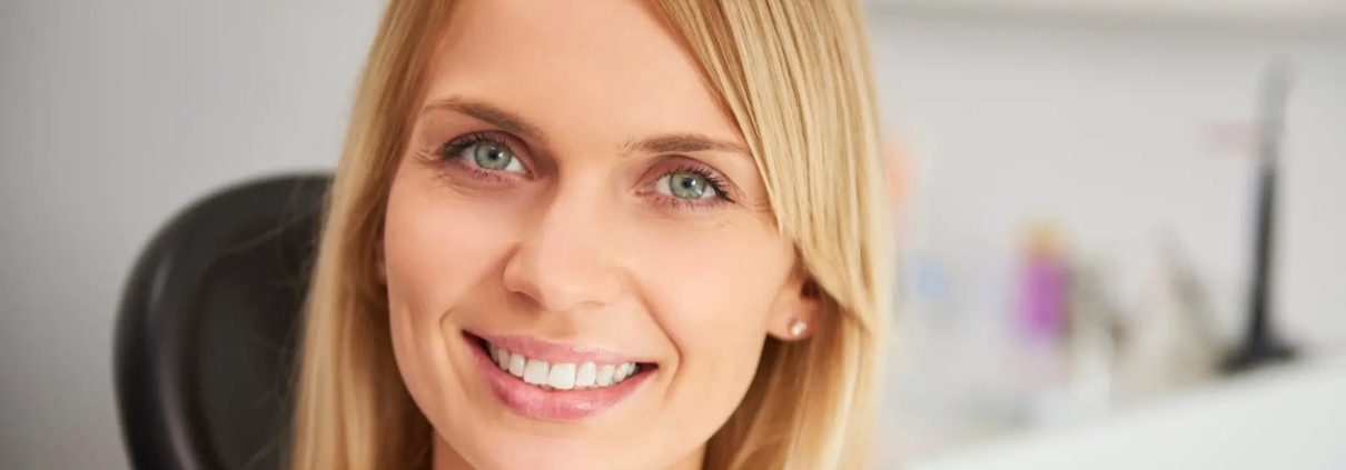 Femme souriante dans une clinique dentaire après un traitement réussi des caries.