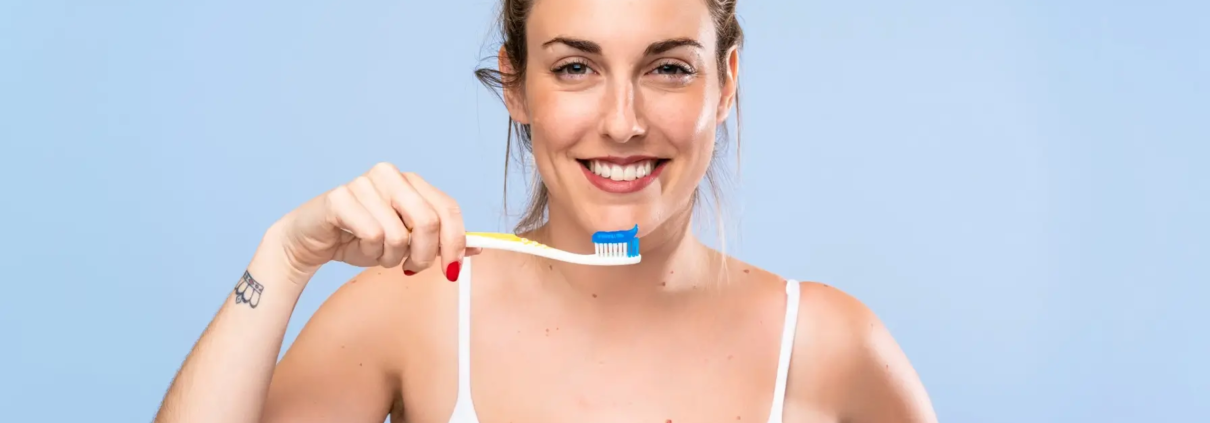 Une femme radieuse, souriant pour démontrer l'importance des produits dentaires de qualité et des techniques de brossage appropriées.