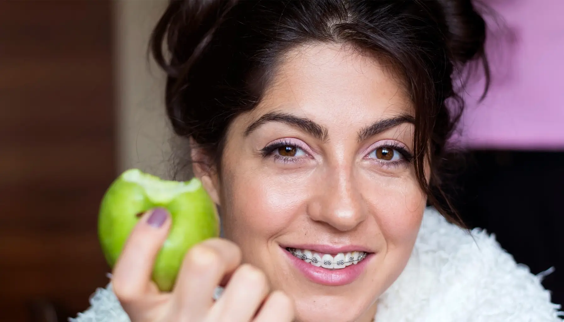 Une femme croquant une pomme, mettant en lumière l'importance d'une alimentation santé dentaire et des visites dentaires régulières.