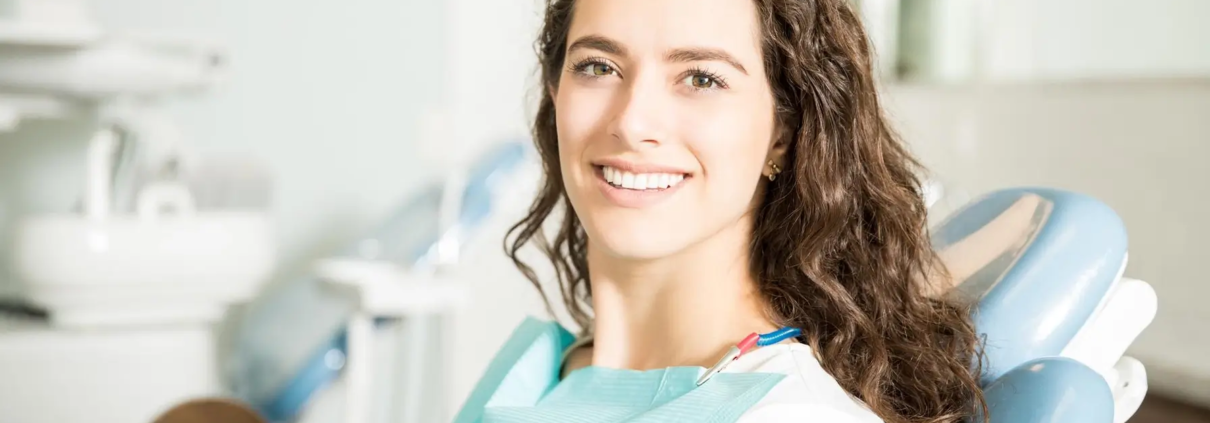 Jeune femme souriante chez le dentiste grâce à une alimentation anti-caries.