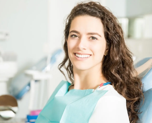 Jeune femme souriante chez le dentiste grâce à une alimentation anti-caries.