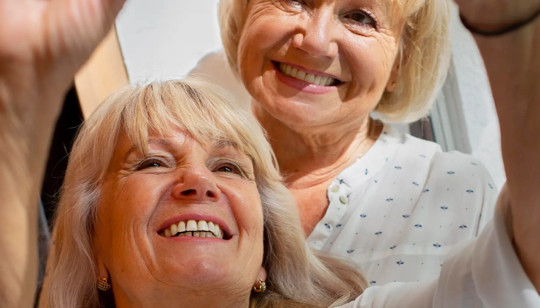 Femme senior joyeuse prenant un selfie montrant ses dents saines, reflétant une bonne hygiène buccale et possiblement des prothèses dentaires bien entretenues.