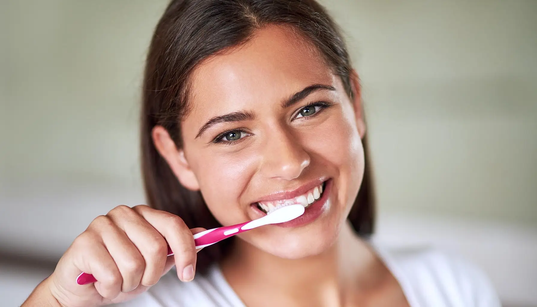 Jeune femme démontrant la technique de brossage des dents sur fond blanc