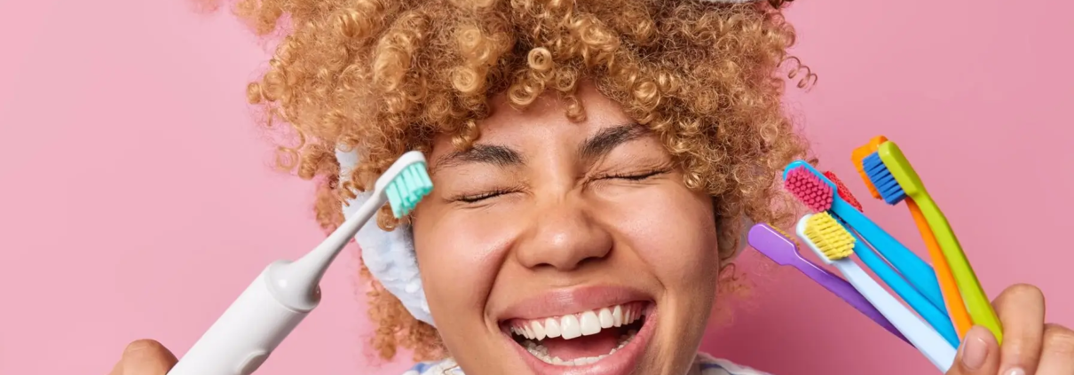 Jeune femme souriante avec des brosses à dents, dents saines grâce à une bonne hygiène bucco-dentaire et un dentifrice anti-caries.