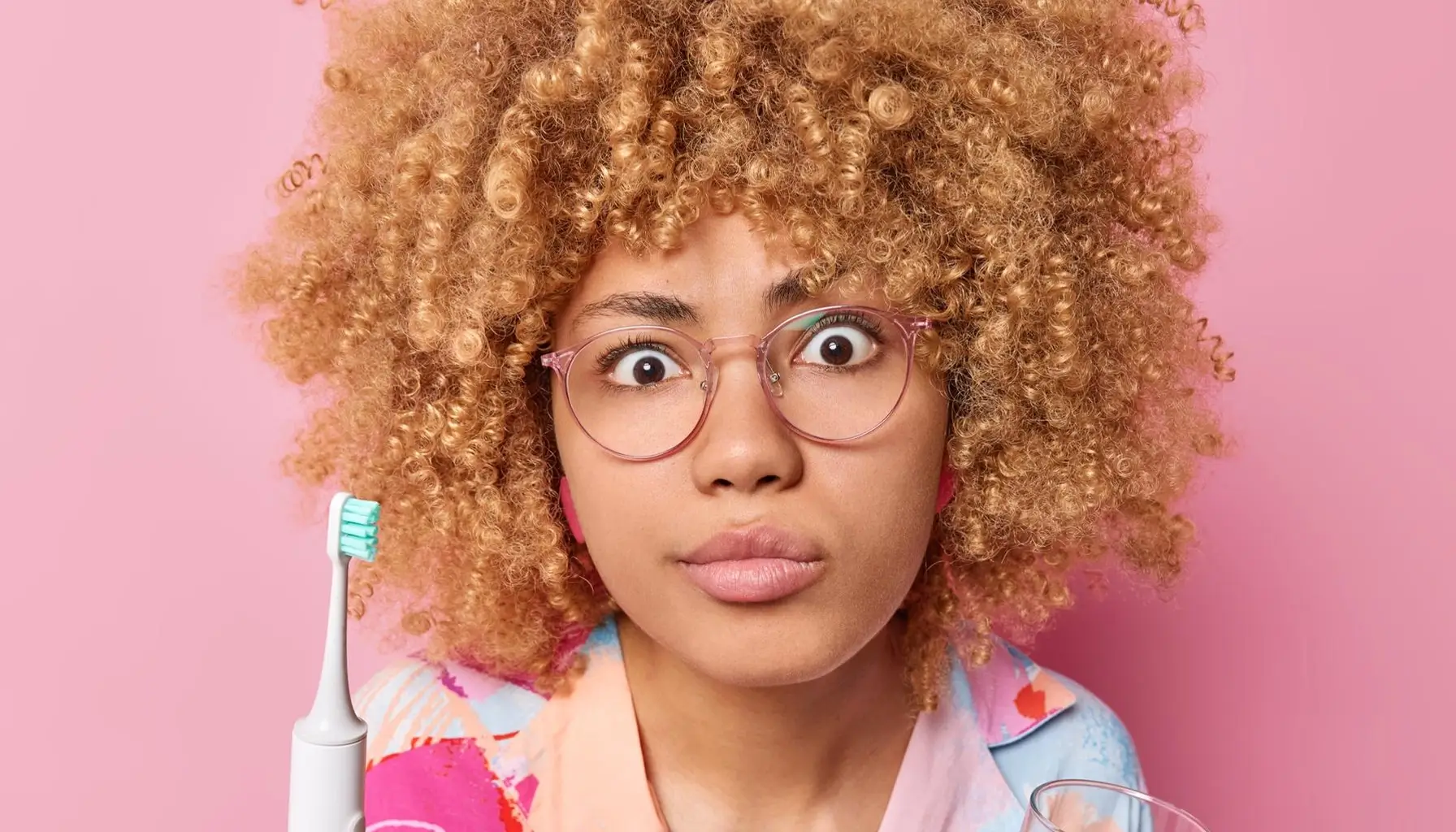 Femme se préparant à se brosser les dents avec une brosse à dents électrique et un bain de bouche, illustrant une hygiène bucco-dentaire quotidienne pour prévenir les caries.