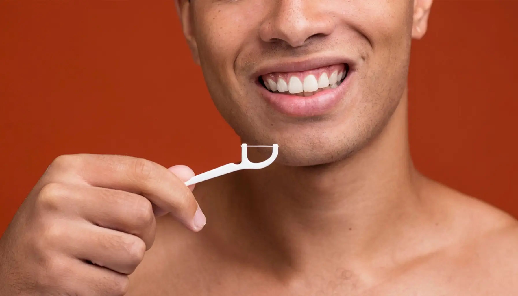 Jeune homme se brossant les dents et utilisant du fil dentaire dans le cadre de sa routine d'hygiène dentaire quotidienne.