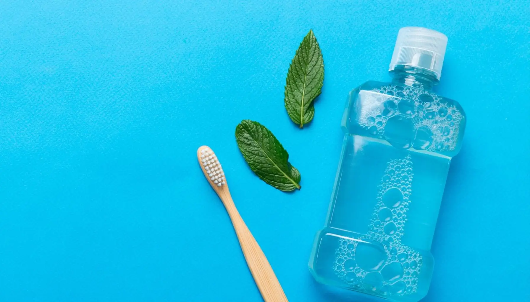 Assortiment de produits d'hygiène buccale, dont des bains de bouche, disposés sur une surface bleue, soulignant l'importance d'une routine dentaire variée.