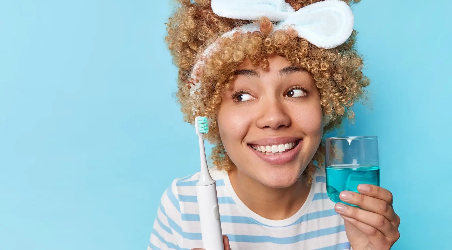 Démonstration d'une routine d'hygiène buccale complète : femme utilisant une brosse à dents et un bain de bouche, soulignant l'importance de combiner différentes méthodes pour une santé dentaire optimale.