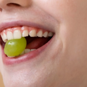 Femme souriante avec raisin, promouvoir une bonne hygiène bucco-dentaire et la prévention des caries dentaires.