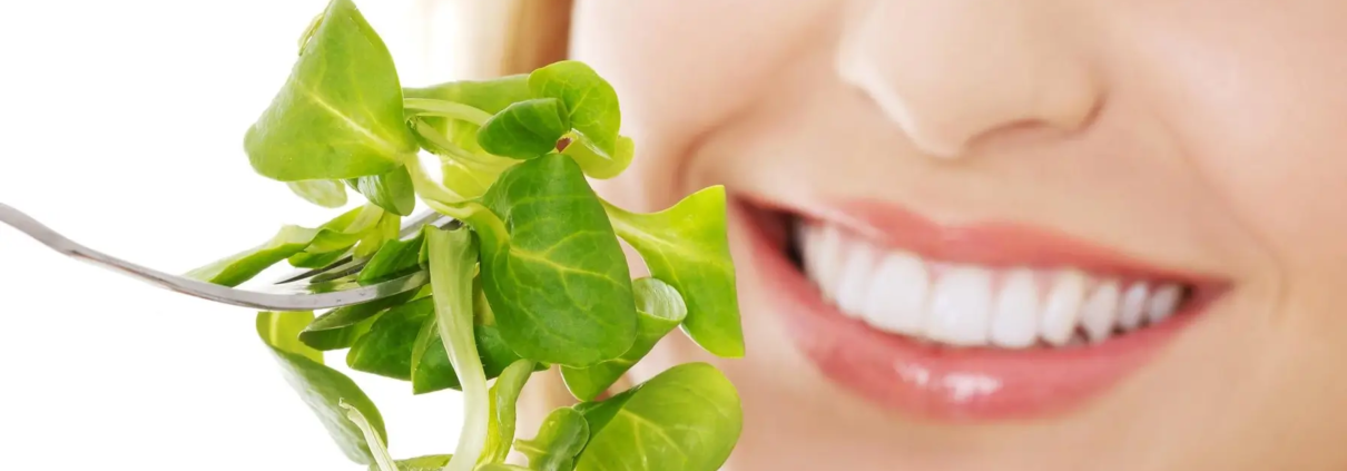 Une femme savoure une salade, illustrant l'importance de l'alimentation dans la prévention des maladies parodontales et le maintien d'une bonne hygiène bucco-dentaire.