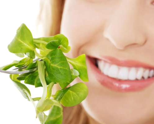 Une femme savoure une salade, illustrant l'importance de l'alimentation dans la prévention des maladies parodontales et le maintien d'une bonne hygiène bucco-dentaire.