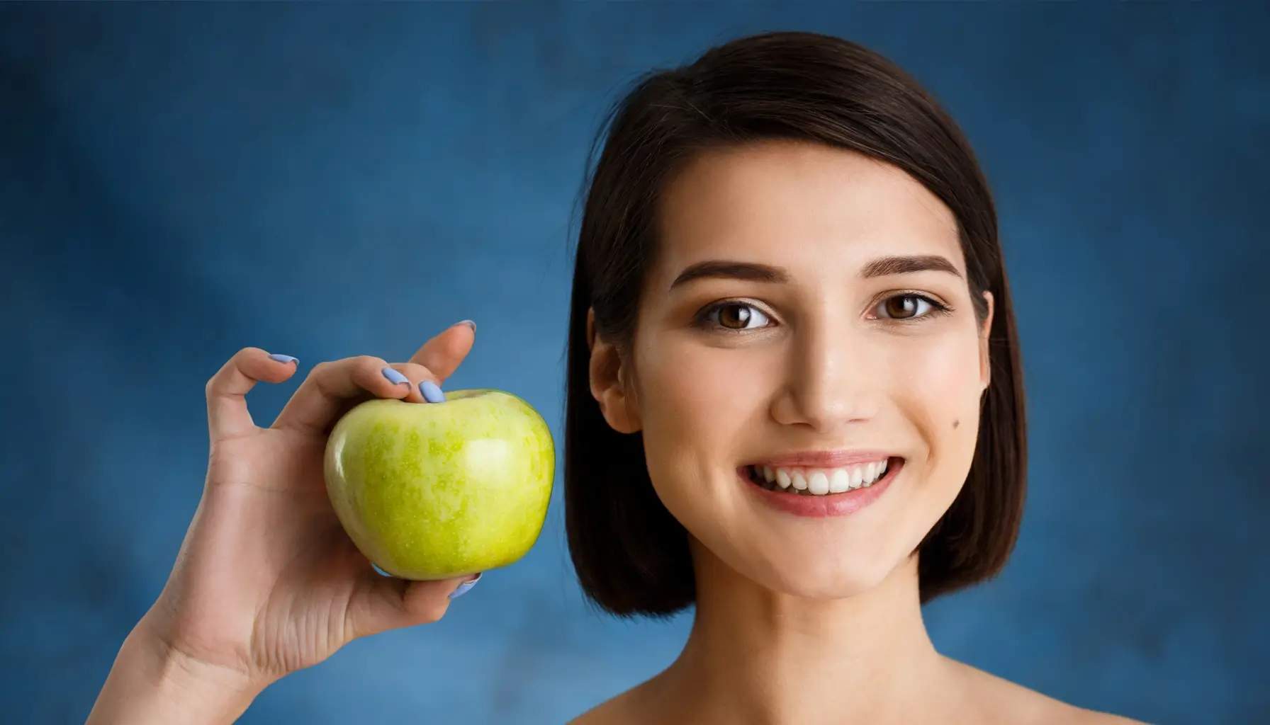 Portrait en gros plan d'une jeune femme délicate tenant une pomme, soulignant l'impact de l'alimentation sur la santé bucco-dentaire et les techniques de prévention.