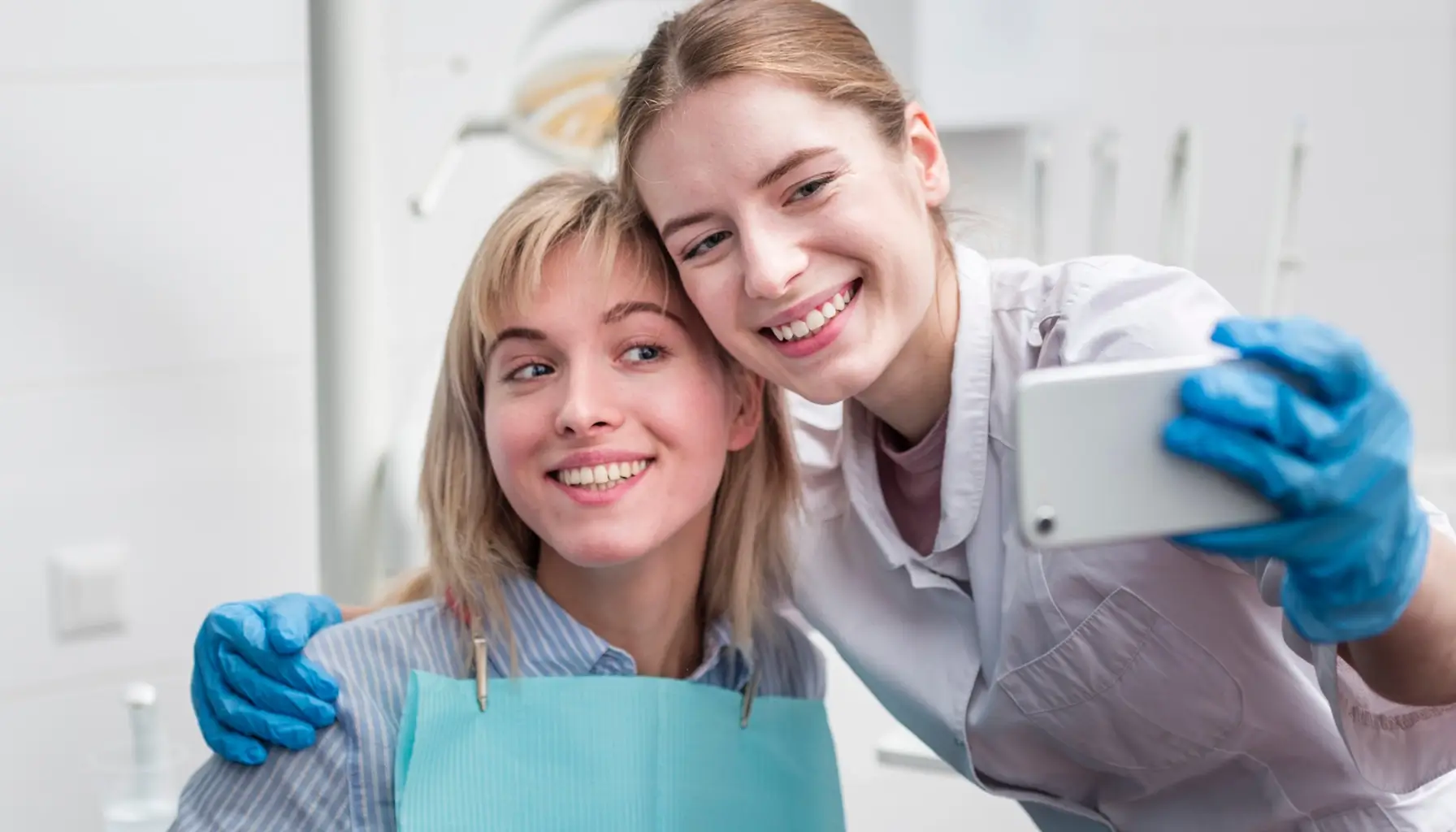 Un dentiste et sa patiente célèbrent le résultat d'une restauration dentaire réussie en prenant un selfie, soulignant l'importance de la santé bucco-dentaire