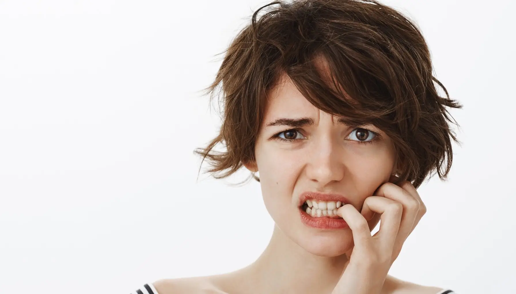 Femme inquiète grimaçant, possiblement en raison de problèmes de santé bucco-dentaire, soulignant le besoin d'un dépistage précoce des maladies dentaires.