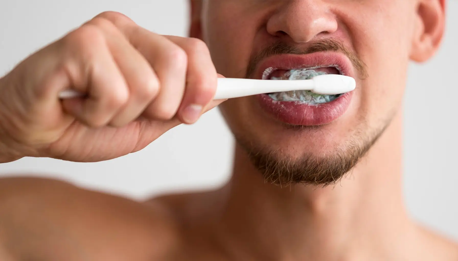 Homme se brossant les dents, un geste simple mais essentiel pour éliminer la plaque dentaire et les bactéries buccales, réduisant ainsi le risque de maladies cardiaques telles que l'endocardite. Des soins dentaires réguliers et une prophylaxie antibiotique peuvent également être recommandés pour prévenir les infections cardiaques.