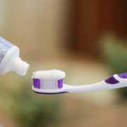 Femme mettant du dentifrice sur sa brosse à dents, un geste quotidien crucial pour l'hygiène bucco-dentaire. Les ingrédients des dentifrices, comme le fluor, aident à protéger les dents, tandis que les formules blanchissantes ou pour dents sensibles répondent à des besoins spécifiques. L'utilisation régulière de dentifrice, associée à des rince-bouches antibactériens, favorise une bonne santé dentaire.