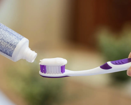 Femme mettant du dentifrice sur sa brosse à dents, un geste quotidien crucial pour l'hygiène bucco-dentaire. Les ingrédients des dentifrices, comme le fluor, aident à protéger les dents, tandis que les formules blanchissantes ou pour dents sensibles répondent à des besoins spécifiques. L'utilisation régulière de dentifrice, associée à des rince-bouches antibactériens, favorise une bonne santé dentaire.