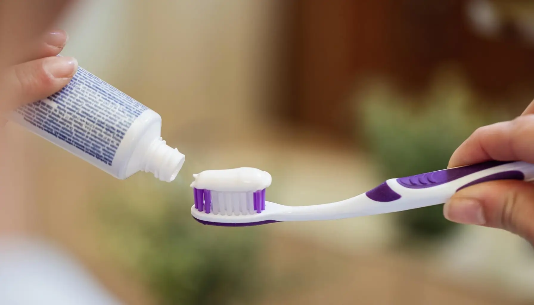 Femme mettant du dentifrice sur sa brosse à dents, un geste quotidien crucial pour l'hygiène bucco-dentaire. Les ingrédients des dentifrices, comme le fluor, aident à protéger les dents, tandis que les formules blanchissantes ou pour dents sensibles répondent à des besoins spécifiques. L'utilisation régulière de dentifrice, associée à des rince-bouches antibactériens, favorise une bonne santé dentaire.