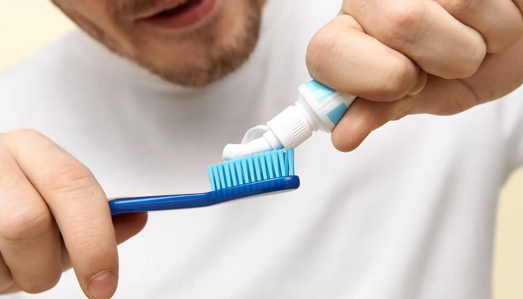 Homme utilisant du dentifrice pour se brosser les dents, un élément clé de l'hygiène bucco-dentaire. Que l'on choisisse des dentifrices au fluor, blanchissants ou pour dents sensibles, leurs ingrédients contribuent à la santé dentaire lorsqu'ils sont utilisés régulièrement, en association avec des rince-bouches antibactériens, pour une routine d'hygiène bucco-dentaire complète.